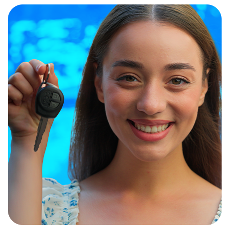 Mulher sorrindo segurando chave de carro na mão, em fundo azul desfocado.