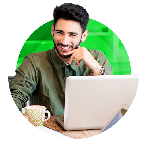 Homem sorrindo em frente ao notebook, em ambiente com elementos verdes.