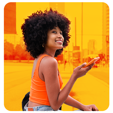 Mulher sorrindo com celular na mão em cenário urbano amarelo e laranja.