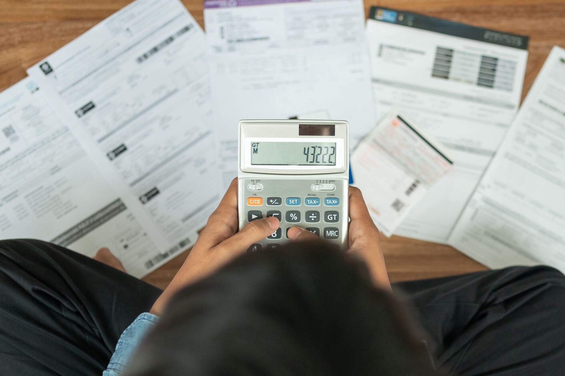 Mãos femininas teclando uma calculadora