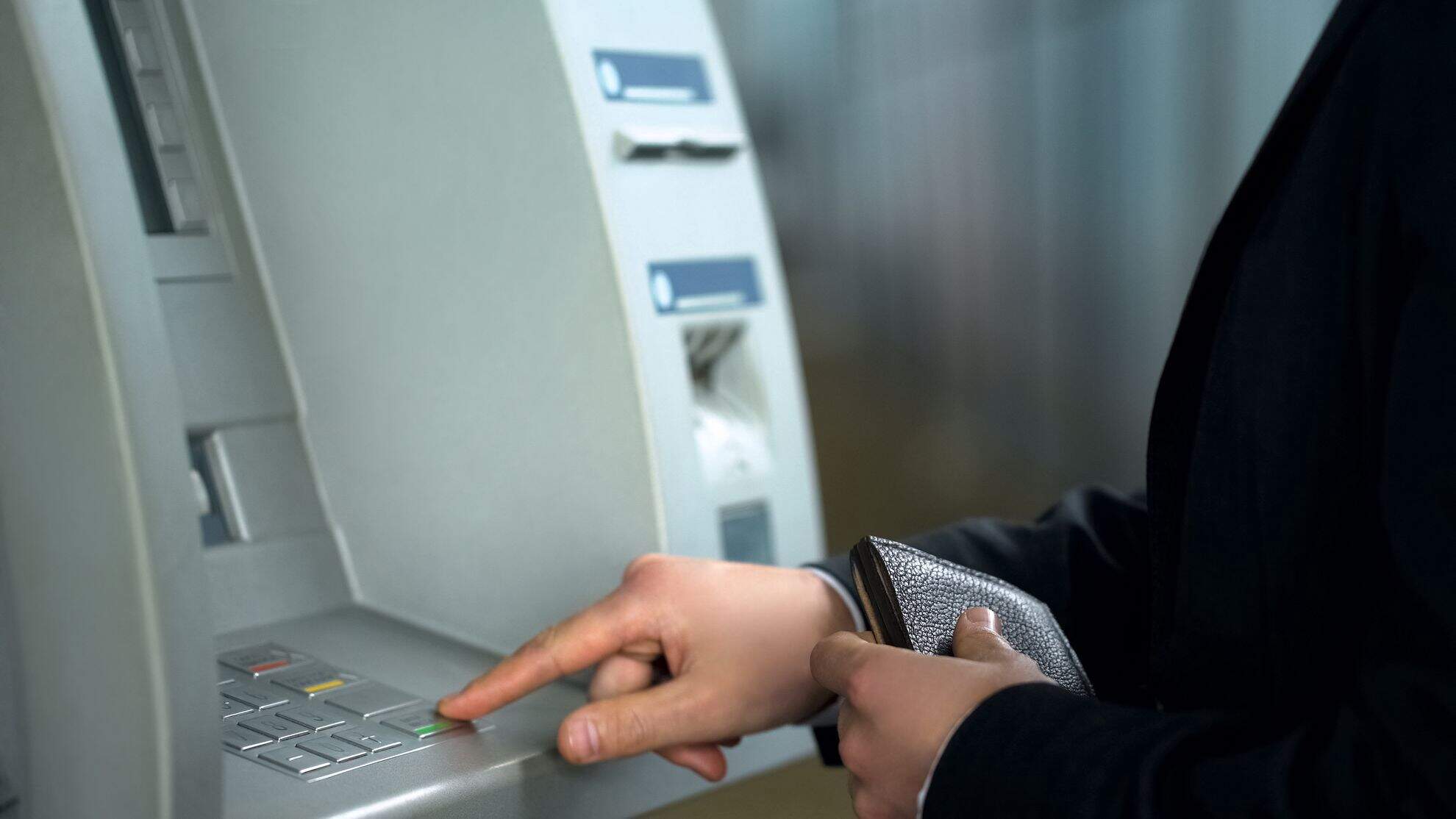 Homem fazendo saque no caixa eletrônico