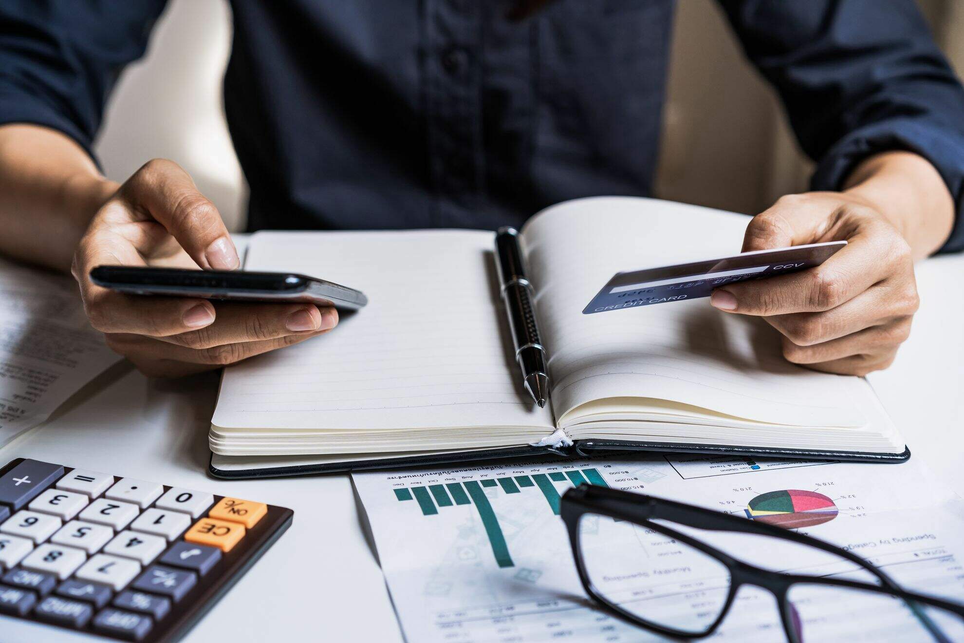 Homem com agenda, calculadora e cartão, fazendo contas para o acordo Santander