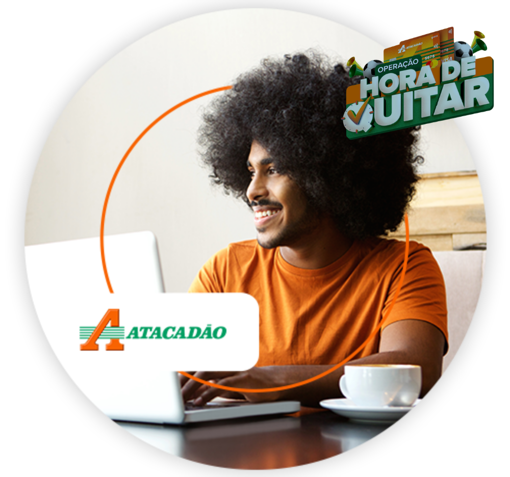 Homem usando notebook em casa, com logo do Atacadão em destaque.