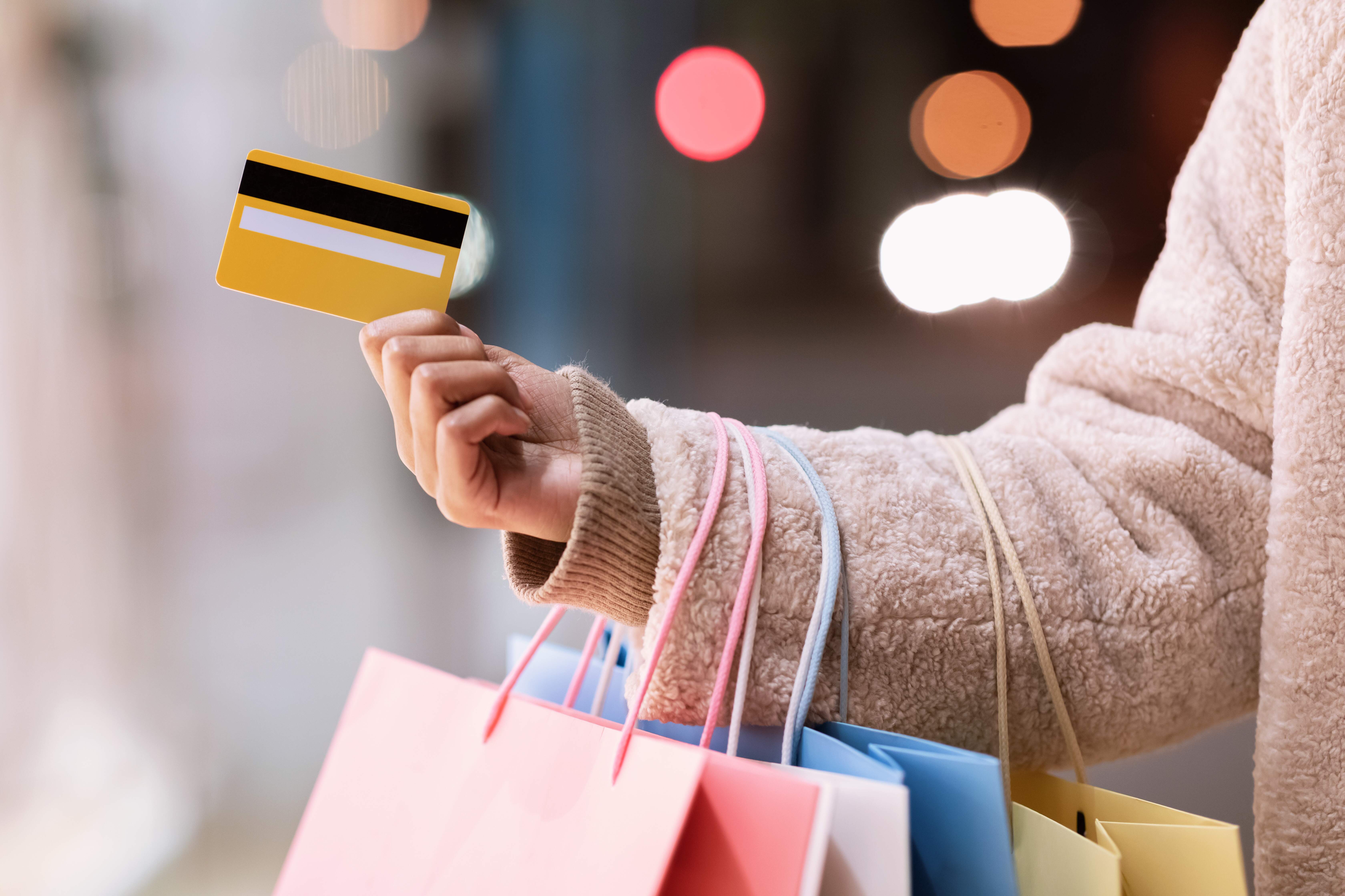 Mão feminina segurando o cartão de crédito e as compras